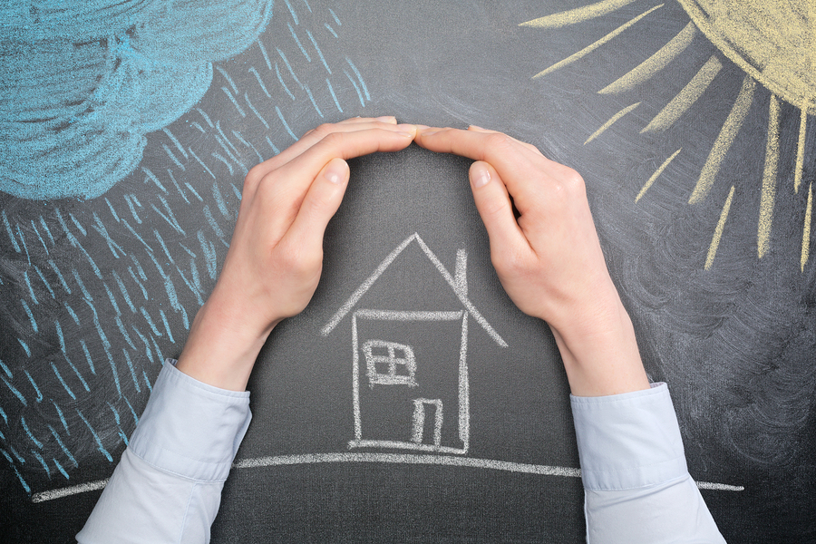 A young businesswoman protects a house from the elements - rain or storm and sun. Blackboard drawing top view.