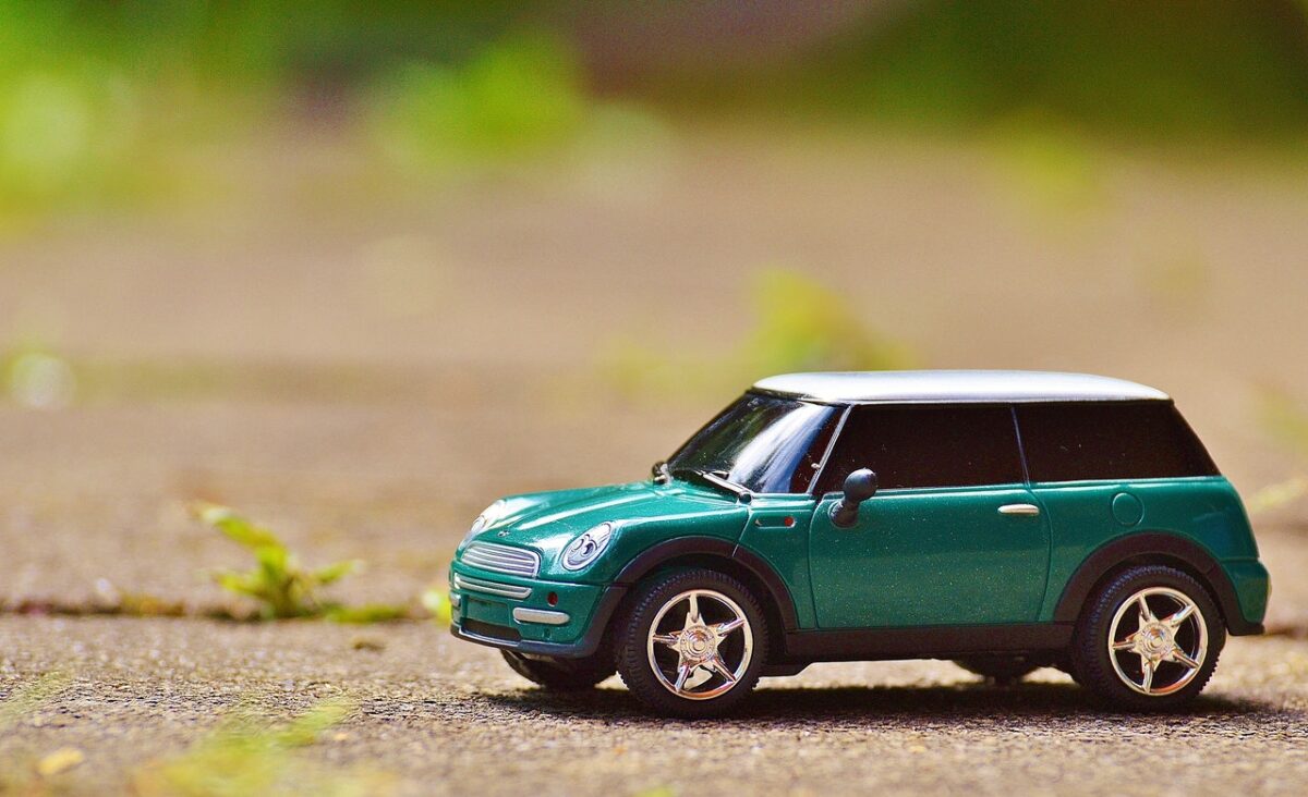green scale model car on brown pavement 35967