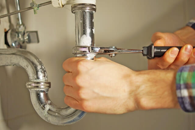 hands fixing a pipe for property insurance